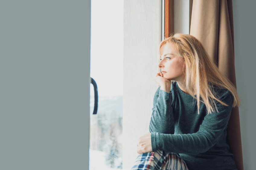 A photo of a woman in a green shirt, while looking out the window.