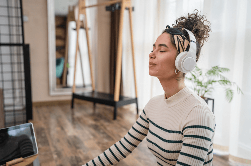 A photo of a woman wearing headphones with her eyes closed, with a slightly smiling expression on her face.