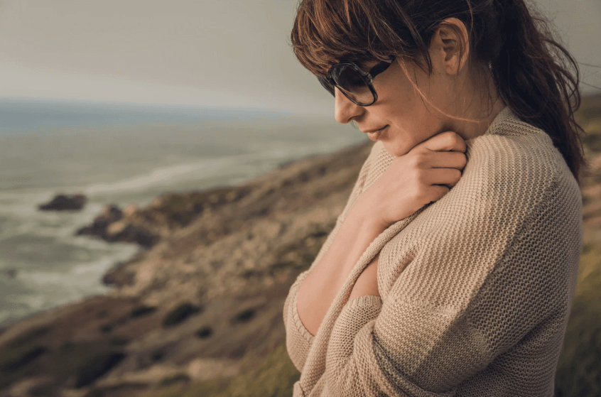 Woman standing with arms crossed outside.