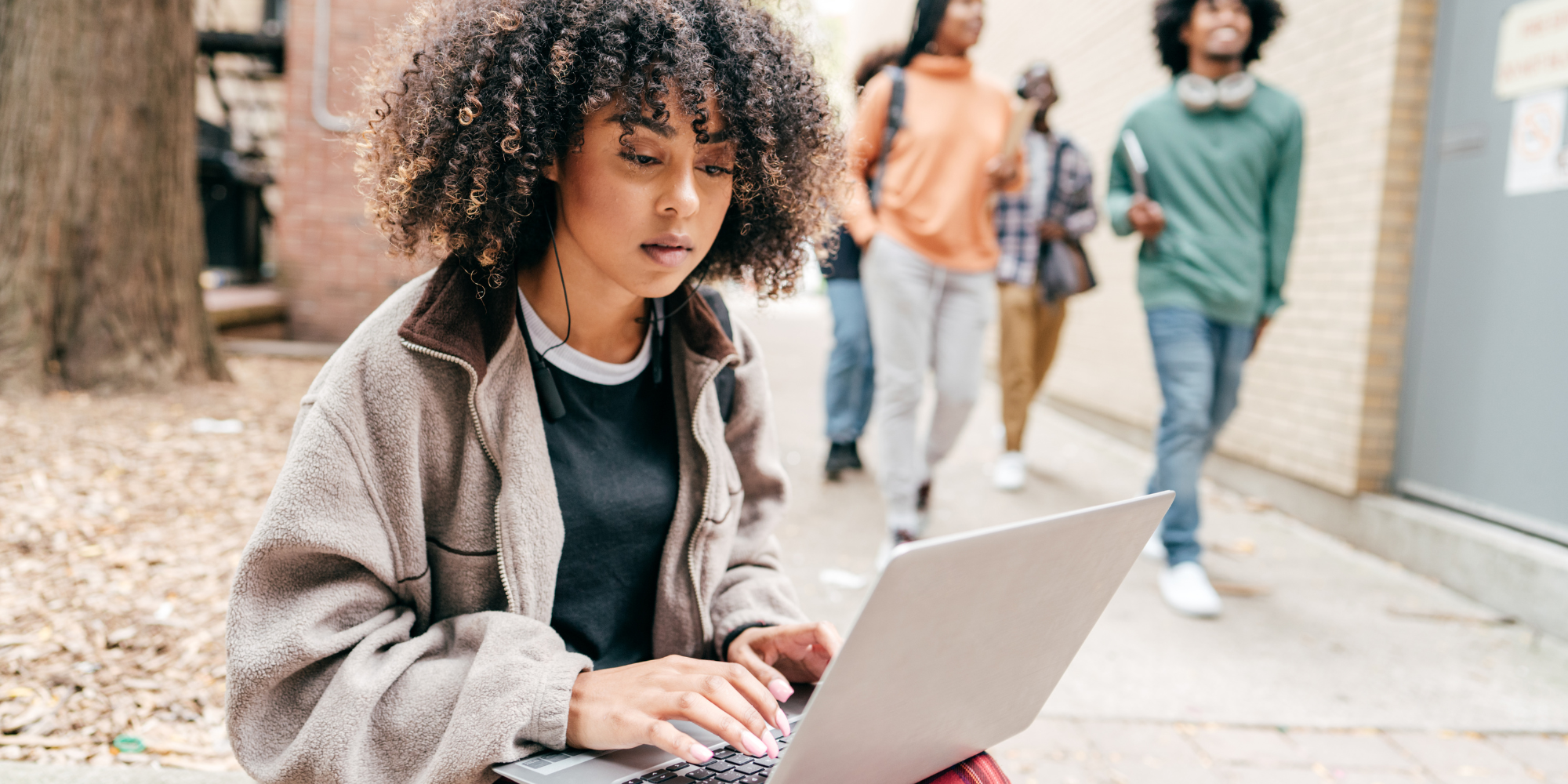 A student working outdoors on a laptop, experiencing college depression.