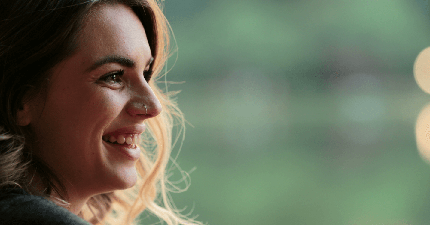 A photo of a woman at an up-close angle smiling and looking to the right.