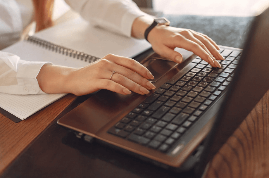 A photo of a woman's hands typing on a computer keyboard.